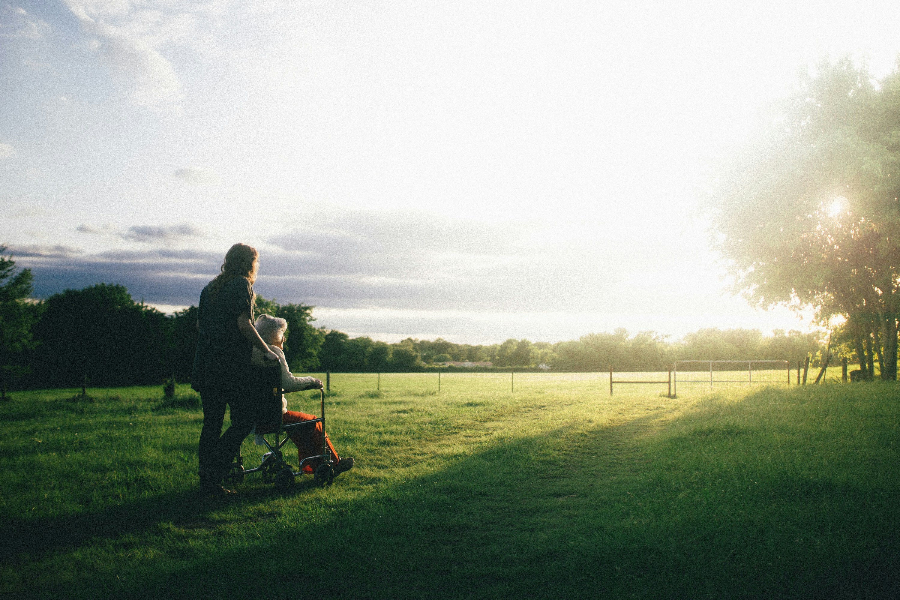 Caregiver supporting a senior in a wheelchair outdoors
